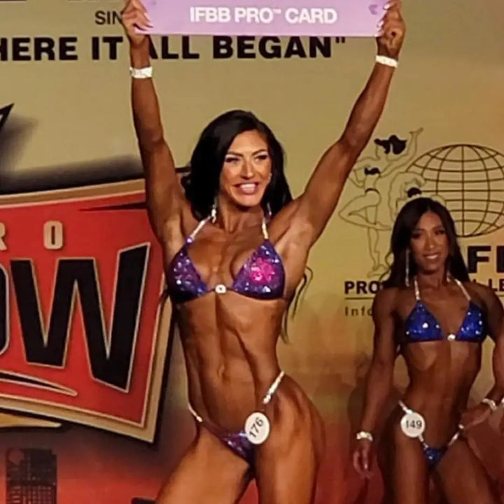 Annelle's Pro Card Nova, the epitome of elegance and strength for NPC Bikini or Wellness athletes. Designed with Annelle Petitpas, it showcases beautiful fuchsia and purple hues in unique designs. Elevate your stage presence with this striking suit, embodying confidence and style like never before.
