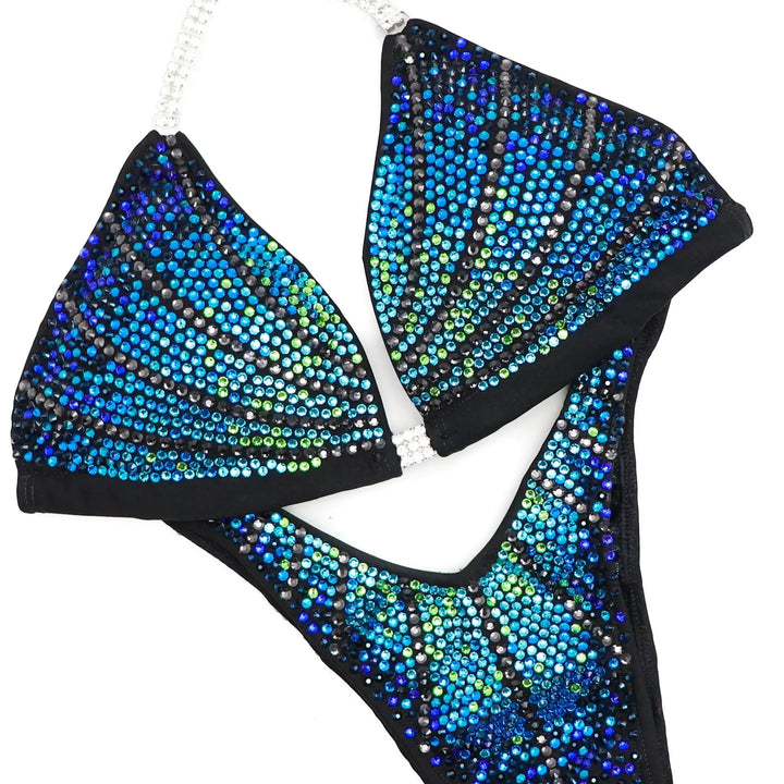 "Unleash your star power with Midnight Seafoam Galaxy! 💫💙 This captivating blue bodybuilding suit boasts a mesmerizing fade of green to blue crystals, ensuring you shine bright on stage. Elevate your performance with this celestial design! #BodybuildingGlam #MidnightSeafoam #GalaxyGlow"