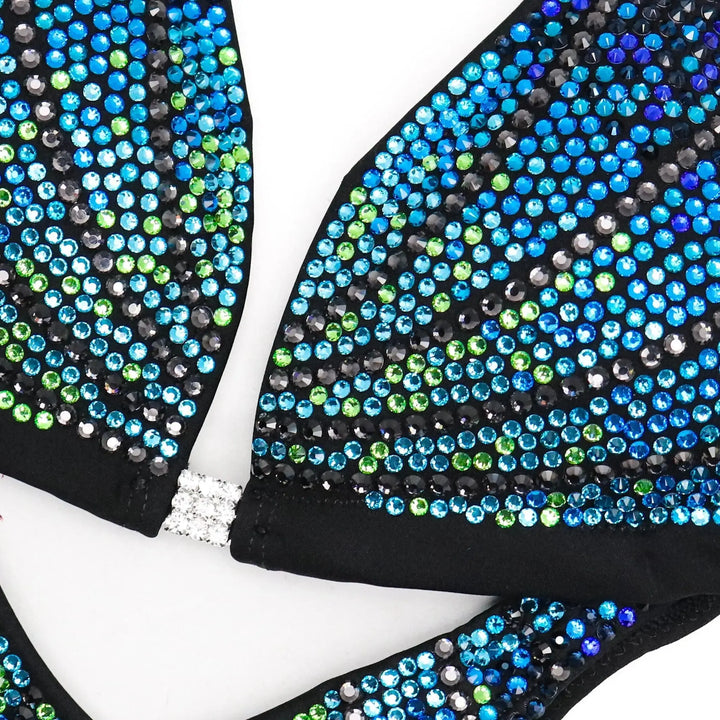 "Unleash your star power with Midnight Seafoam Galaxy! 💫💙 This captivating blue bodybuilding suit boasts a mesmerizing fade of green to blue crystals, ensuring you shine bright on stage. Elevate your performance with this celestial design! #BodybuildingGlam #MidnightSeafoam #GalaxyGlow"