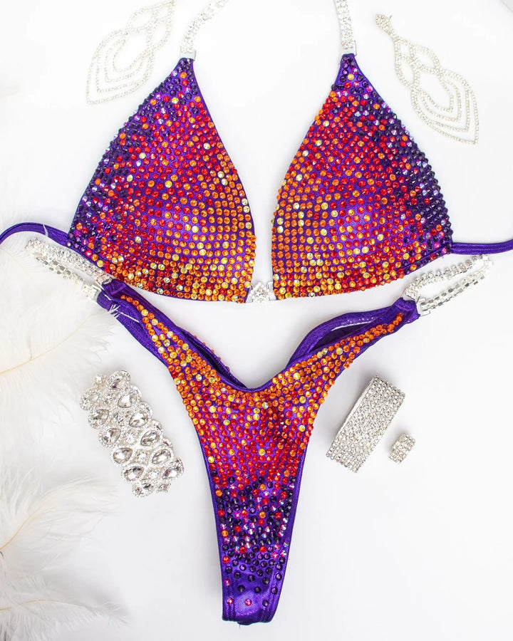 Purple Rainbow Trinity. Our custom-designed Purple Competition Suit is crafted for NPC Bikini and Wellness competitions, exuding charm with meticulous crystal work. This Purple Wellness Bikini, available at Angel Competition Bikinis, complements a wide range of skin tones, embodying both style and fitness.