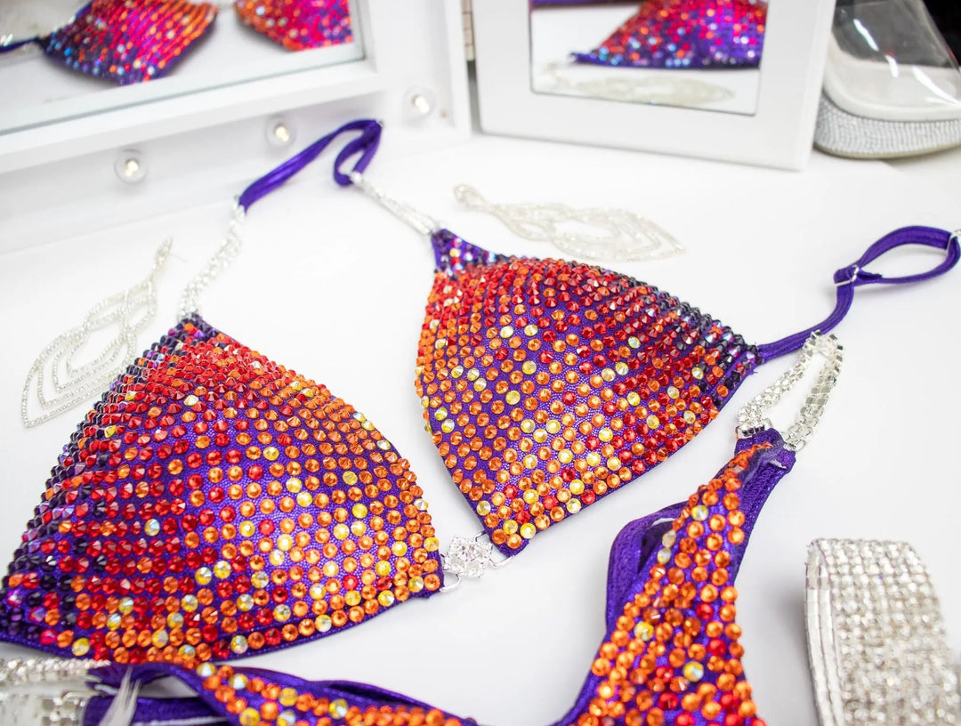 Purple Rainbow Trinity. Our custom-designed Purple Competition Suit is crafted for NPC Bikini and Wellness competitions, exuding charm with meticulous crystal work. This Purple Wellness Bikini, available at Angel Competition Bikinis, complements a wide range of skin tones, embodying both style and fitness.