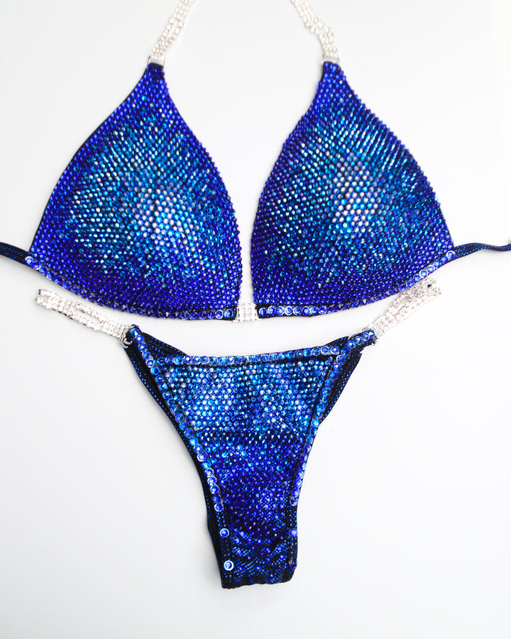 "Introducing Midnight Sapphire Nova! 💙✨ This mesmerizing blue bodybuilding suit features a stunning fade of blue crystals, from light to dark, ensuring you dazzle on stage. Elevate your presence with this show-stopping design! #BodybuildingElegance #MidnightSapphire #NovaDesigns"