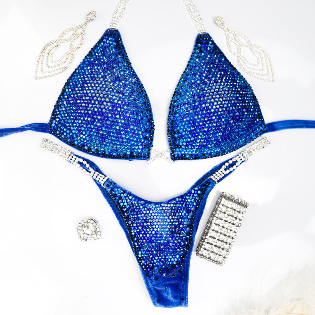 Introducing Casey's Velvet Return Royal Nova, a standout competition suit for female bodybuilders. Crafted from luxurious royal velvet fabric, its stunning blue hues guarantee you shine on stage. Be the one to stand out with this unique and gorgeous suit.