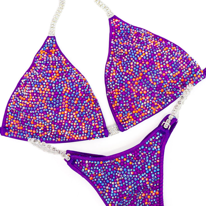 Shine with **Sunshade Aura Radiance**—a stunning hologram purple suit with neon orange & purple crystals for a bold, bright stage statement.
