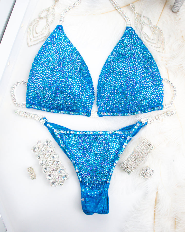  Lauren's Turquoise Radiance, tailored for NPC Bikini or Wellness Competitors. Inspired by Lauren Dannenmiller's iconic suit, this design radiates elegance and confidence. Command the stage and stand out as a true champion in this exclusive creation.