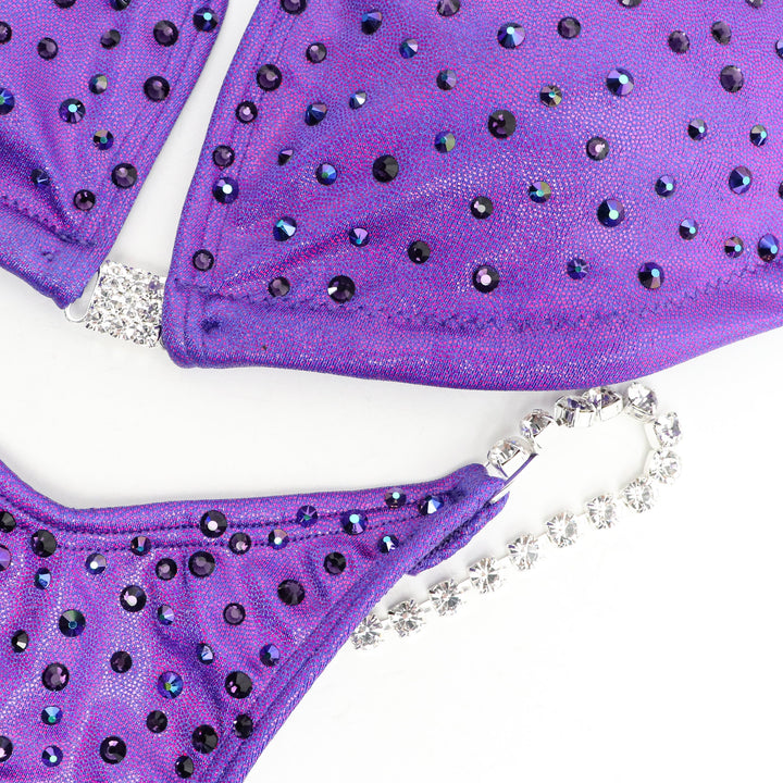Introducing the Victorious Violet Angel Dust: a sleek and stunning competition suit for female bodybuilders! 💜✨ This purple beauty features a subtle scatter of crystals that shimmer effortlessly on stage, enhancing your presence with elegance and simplicity. Stand out confidently and shine bright! #BodybuildingSuit #CompetitionReady #VictoriousVioletAngelDust