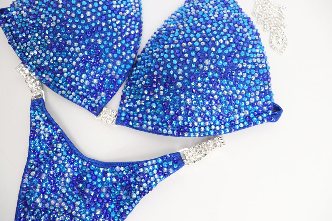 Introducing Rachel's Blue Radiance 💙! This electric blue competition suit features an array of sparkling blue crystals, flattering every skin tone and ensuring you shine like Rachel Schatz on stage. #Bodybuilding #CompetitionSuit #BlueRadiance 💎👙✨