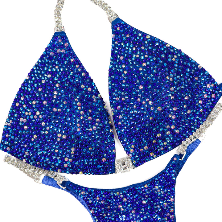 Introducing Crystal Azure Radiance, the epitome of elegance for female bodybuilding competitors. This shimmering blue suit is designed to light up the stage, igniting your inner confidence
