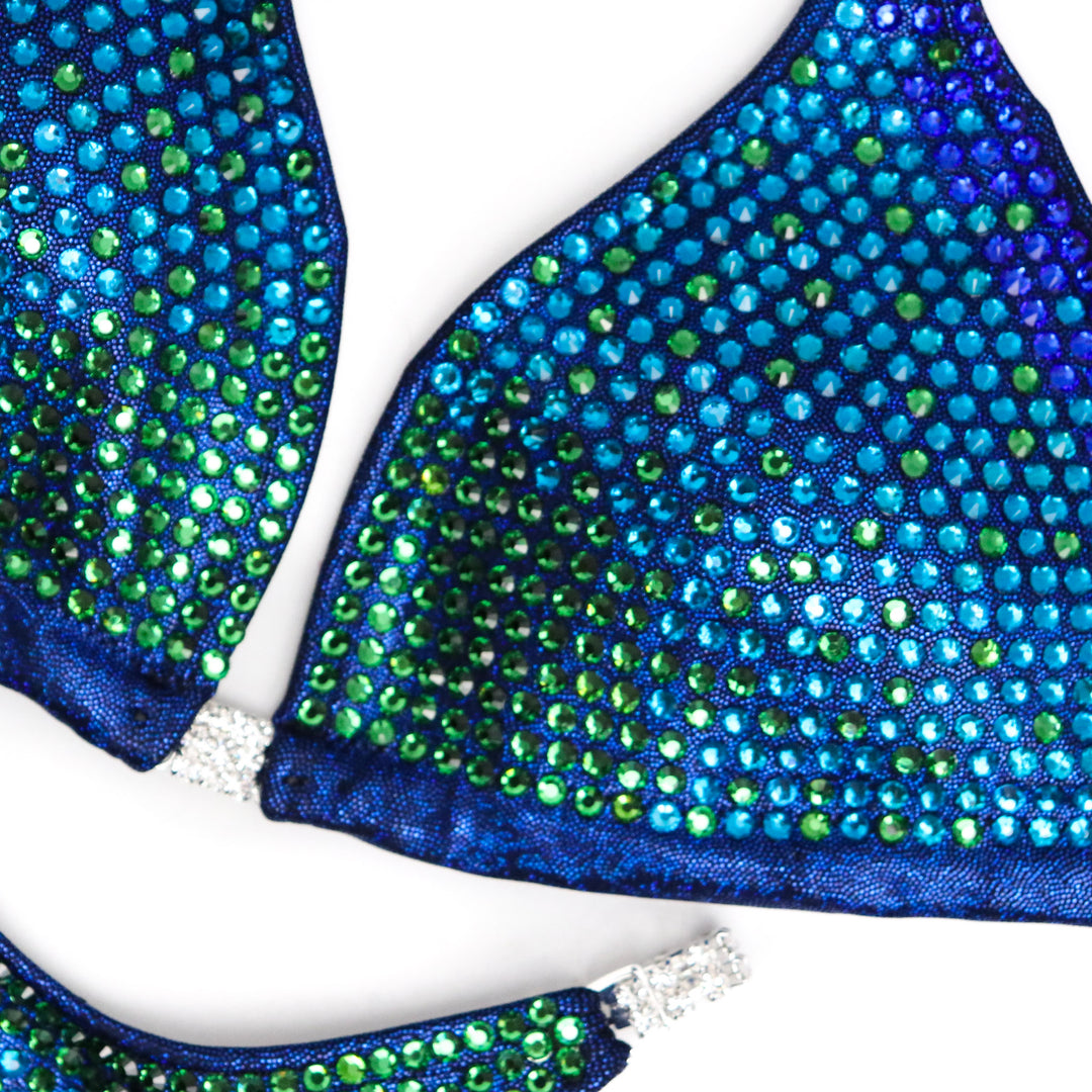 Introducing Casey's Jungle Trinity, a stunning competition suit inspired by Casey DeLong. With captivating blues and greens, this suit ensures you shine on stage. Designed for all female competitors, it combines style and functionality for a show-stopping performance.