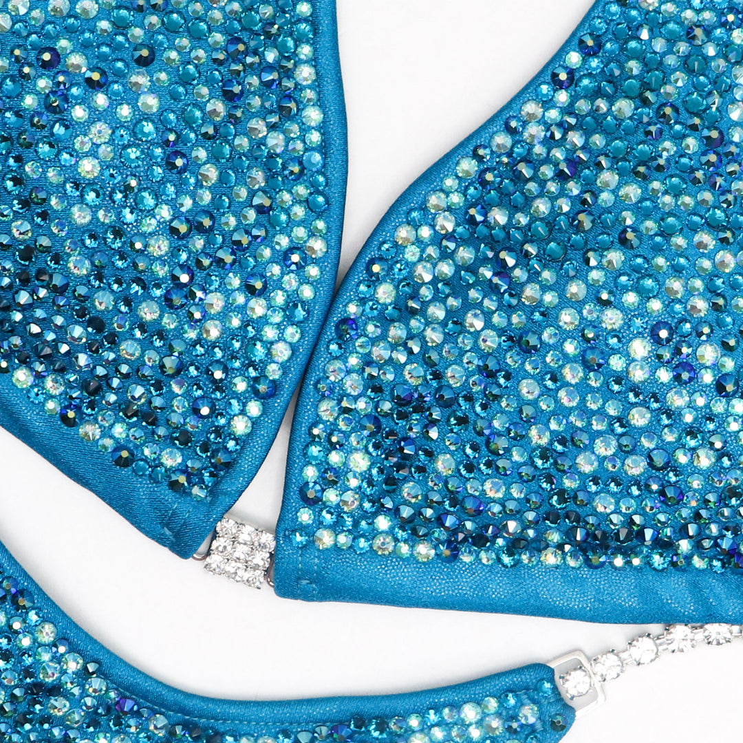 Step into the spotlight with our Ocean Water Radiance competition suit designed for female bikini competitors. Inspired by the tranquil hues of the ocean, this suit shimmers with elegance. Flaunt your physique with confidence and grace. Stand out and shine on stage.