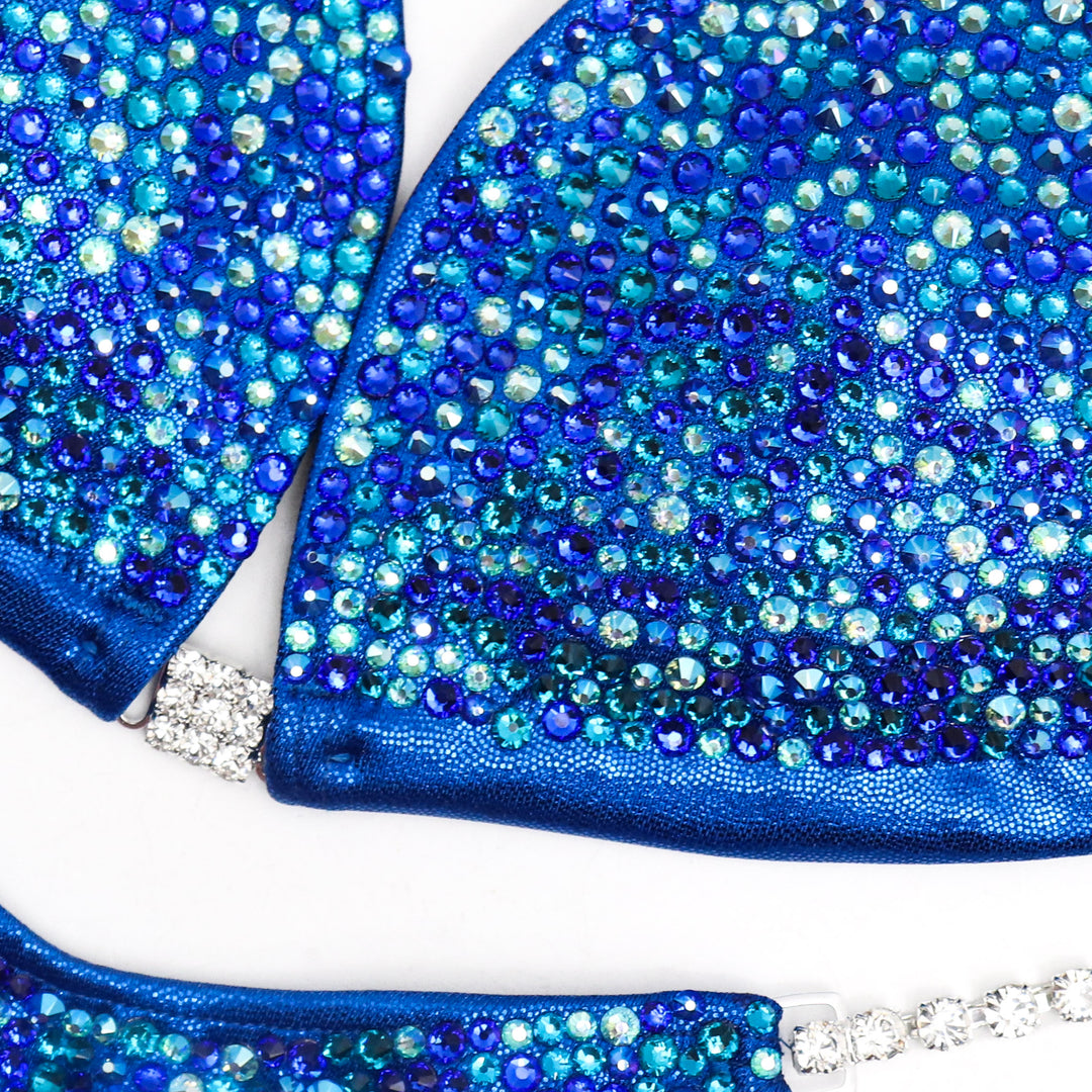 The Blue Shimmer Crystal Radiance competition suit for NPC Bikini or Wellness competitors. Dazzle on stage with its captivating blue sparkle and crystal embellishments. Command attention with elegance and confidence. Elevate your performance and shine like never before.