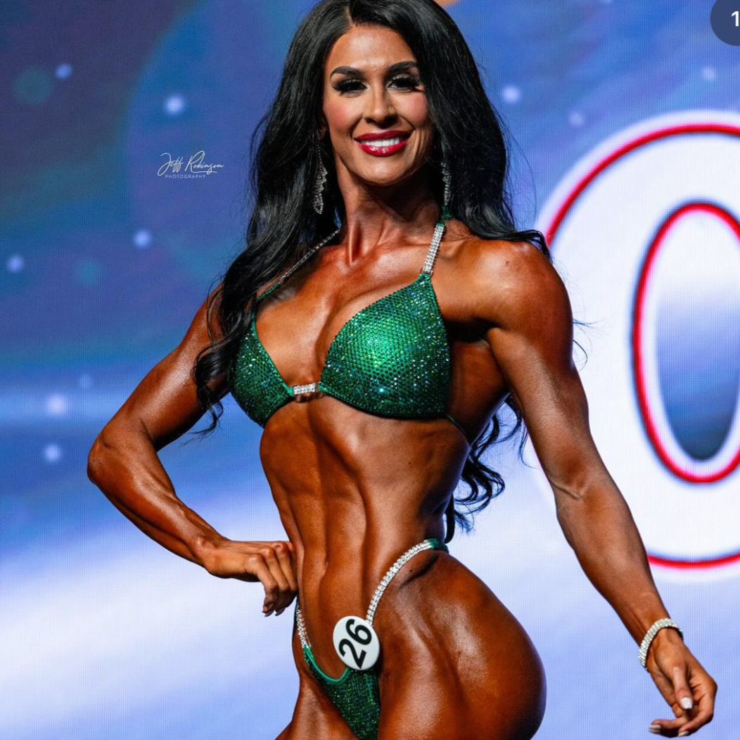 Ashley Kaltwasser's Lucky Charm Nova Competition Suit for NPC Bikini Competitors in vibrant green. Elevate your stage presence with this captivating design. Shine like a charm and dominate with confidence. Stand out as a true champion in this exclusive suit.