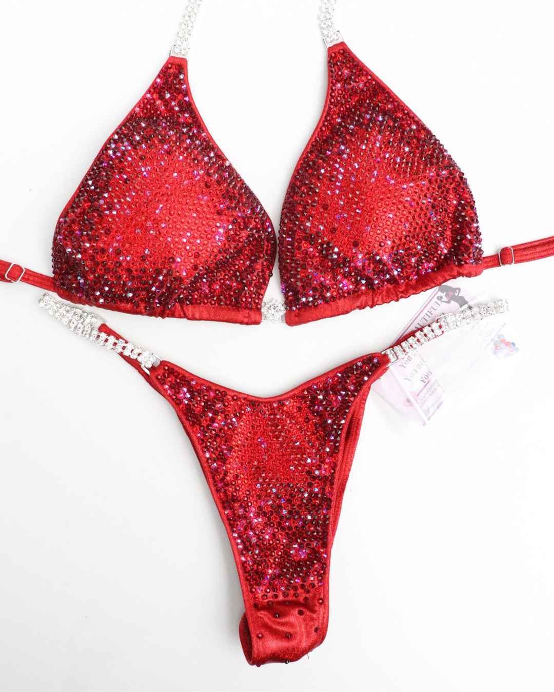 Ashley B's Red Nova, a competition suit inspired by Ashley Bowden and Amber Callahan. Crafted for NPC competitors, it boasts vibrant red hues and a brilliant shine, ensuring you stand out on stage. Elevate your performance with this sleek, eye-catching design. Angel Competition Bikinis will always root for you!