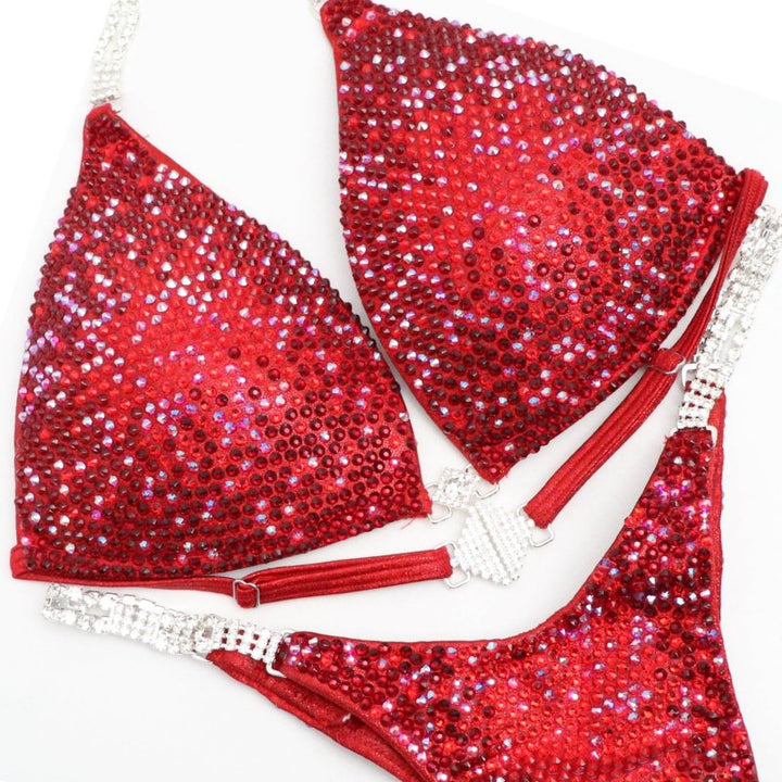 Ashley B's Red Nova, a competition suit inspired by Ashley Bowden and Amber Callahan. Crafted for NPC competitors, it boasts vibrant red hues and a brilliant shine, ensuring you stand out on stage. Elevate your performance with this sleek, eye-catching design. Angel Competition Bikinis will always root for you!