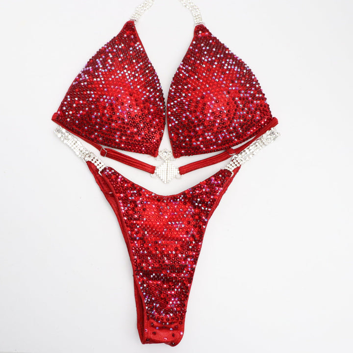 Ashley B's Red Nova, a competition suit inspired by Ashley Bowden and Amber Callahan. Crafted for NPC competitors, it boasts vibrant red hues and a brilliant shine, ensuring you stand out on stage. Elevate your performance with this sleek, eye-catching design. Angel Competition Bikinis will always root for you!