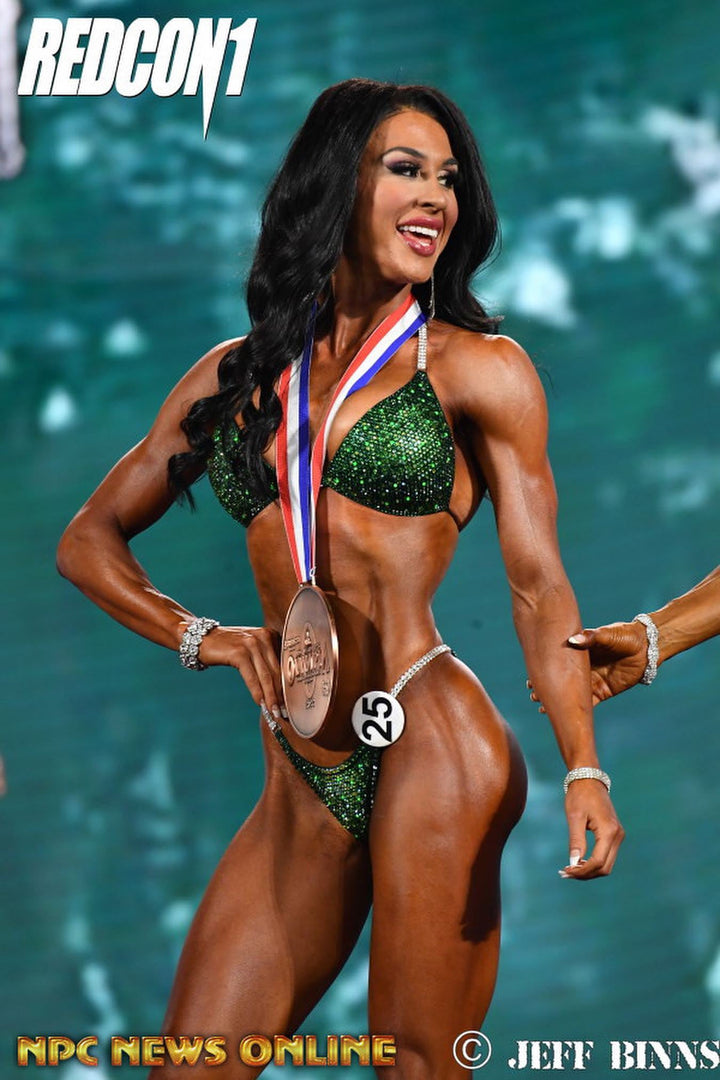 Introducing Ashley's Sweet Pea Nova, an emerald suit with sprinkles of sunflower, beautifully unique and flattering for all female bodybuilders. Stand out on stage with this captivating design that compliments every physique. Inspired by Ashley Kaltwasser's Olympia suit.