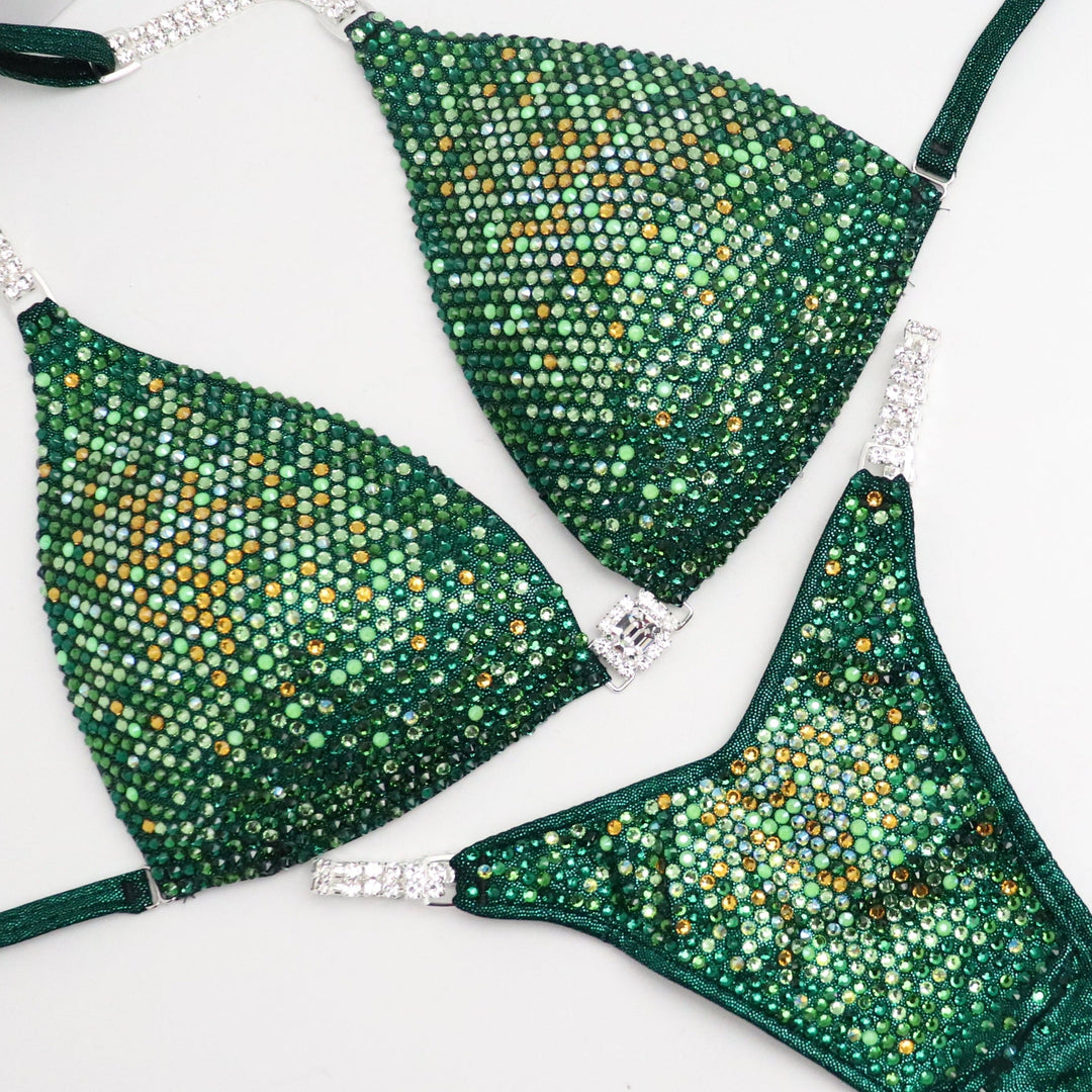 Introducing Ashley's Sweet Pea Nova, an emerald suit with sprinkles of sunflower, beautifully unique and flattering for all female bodybuilders. Stand out on stage with this captivating design that compliments every physique. Inspired by Ashley Kaltwasser's Olympia suit.