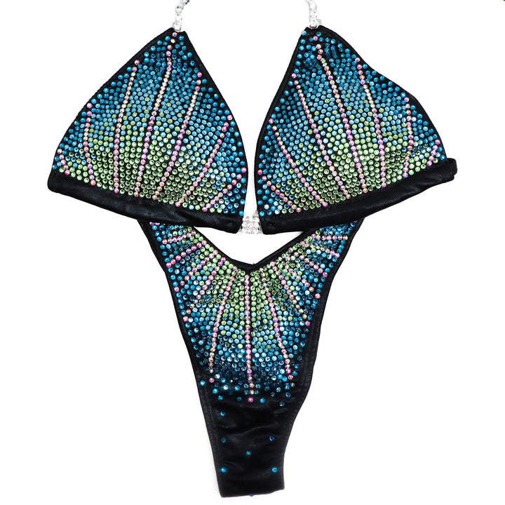 The Blue Zircon Crystal Cosmo competition suit, crafted for female figure competitors and bodybuilders. Elevate your stage presence with its stunning blue zircon crystals, enhancing your physique while commanding attention. Perfect fit, unmatched elegance. Dominate the stage in style.