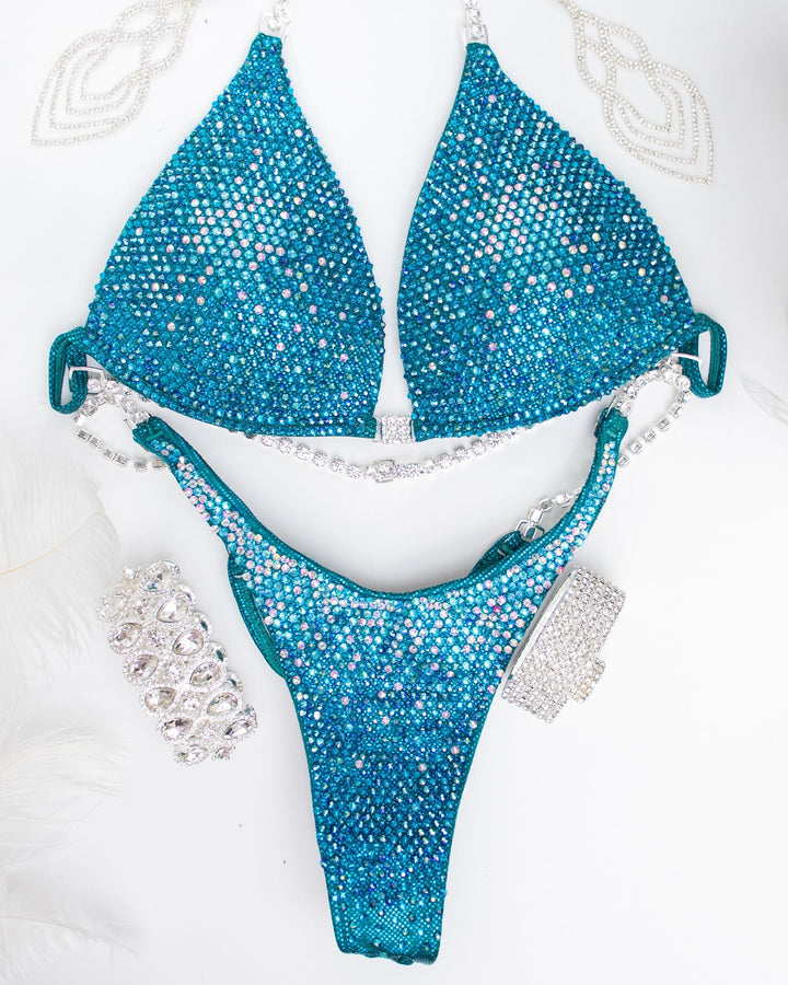 Introducing the Teal Nova competition suit, a stunning teal masterpiece adorned with Aqua AB, Crystal AB, Emerald AB, and Blue Zircon crystals. ✨🌟 Perfect for female bodybuilders seeking elegance and class on stage. Elevate your presence with this exquisite blend of sparkle and sophistication! #Bodybuilding #CompetitionSuit #TealNova #FemaleAthlete