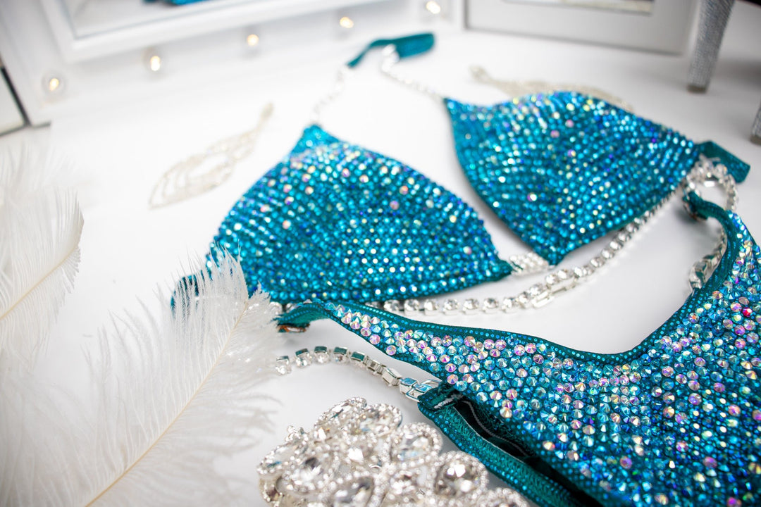 Introducing the Teal Nova competition suit, a stunning teal masterpiece adorned with Aqua AB, Crystal AB, Emerald AB, and Blue Zircon crystals. ✨🌟 Perfect for female bodybuilders seeking elegance and class on stage. Elevate your presence with this exquisite blend of sparkle and sophistication! #Bodybuilding #CompetitionSuit #TealNova #FemaleAthlete