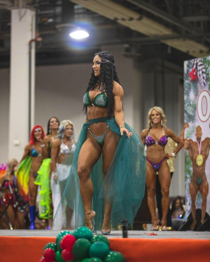 Nina's Emerald Nova Competition Suit, tailored for NPC Bikini or Wellness Competitors. Dazzle on stage with its beautifully radiant green hue, exuding elegance and confidence. Elevate your performance, shine like a star, and make every moment count.